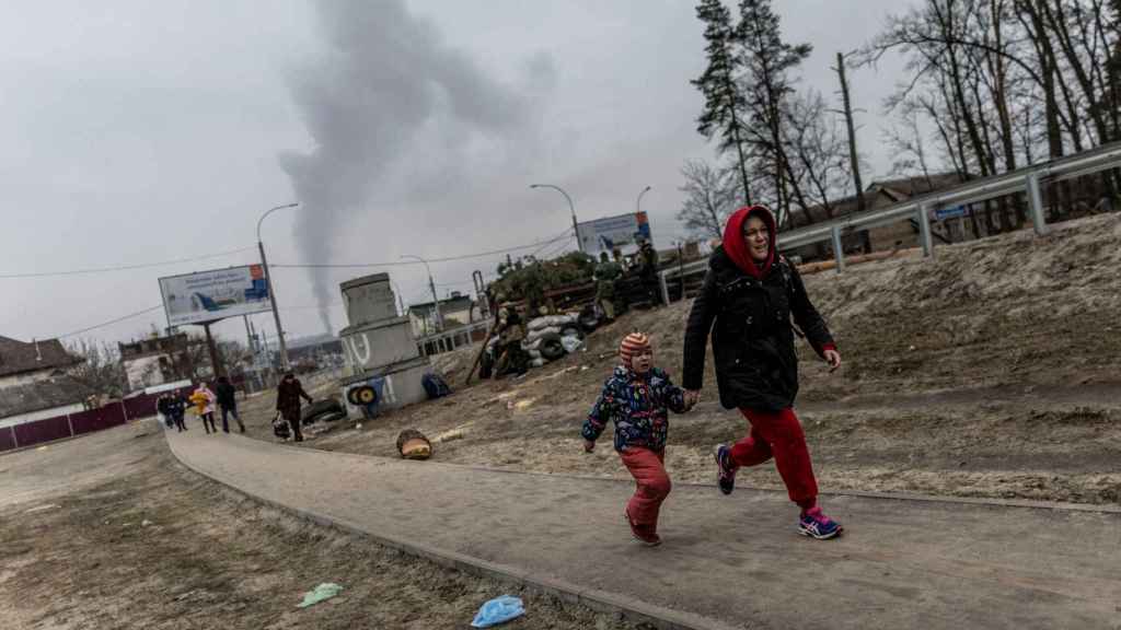 Los residentes locales corren para ponerse a cubierto en Irpin, después de fuertes bombardeos, en marzo de 2022.
